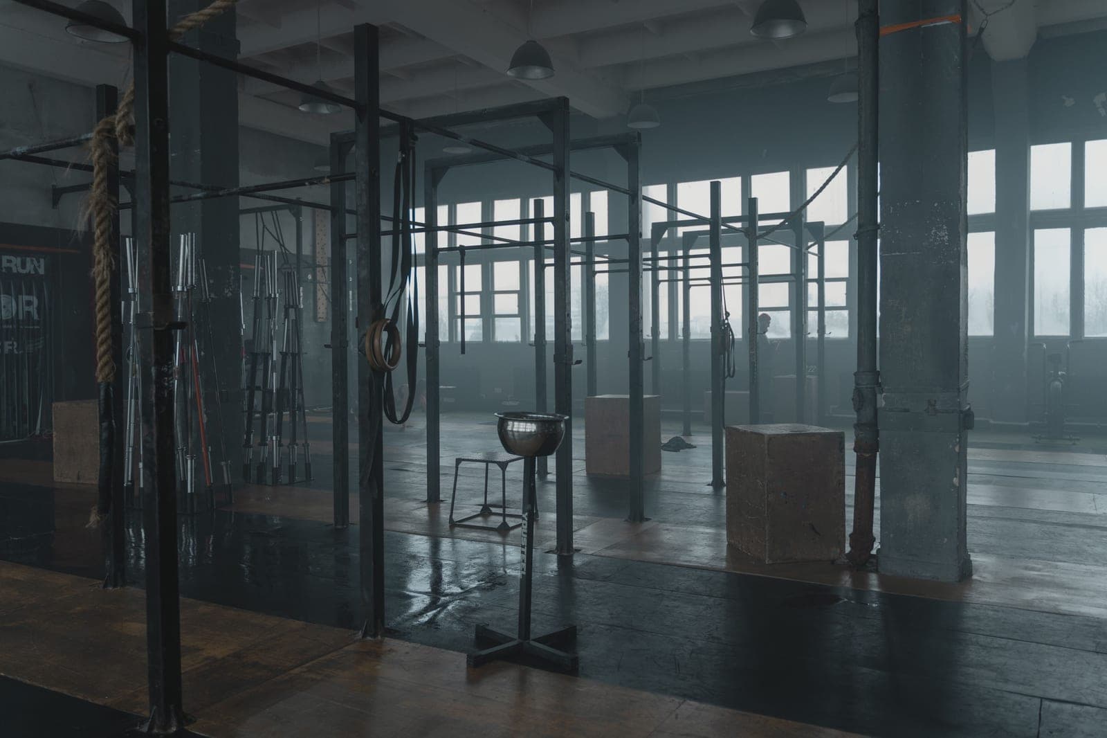 A moody gym interior with pull-up bars and ropes in an industrial space